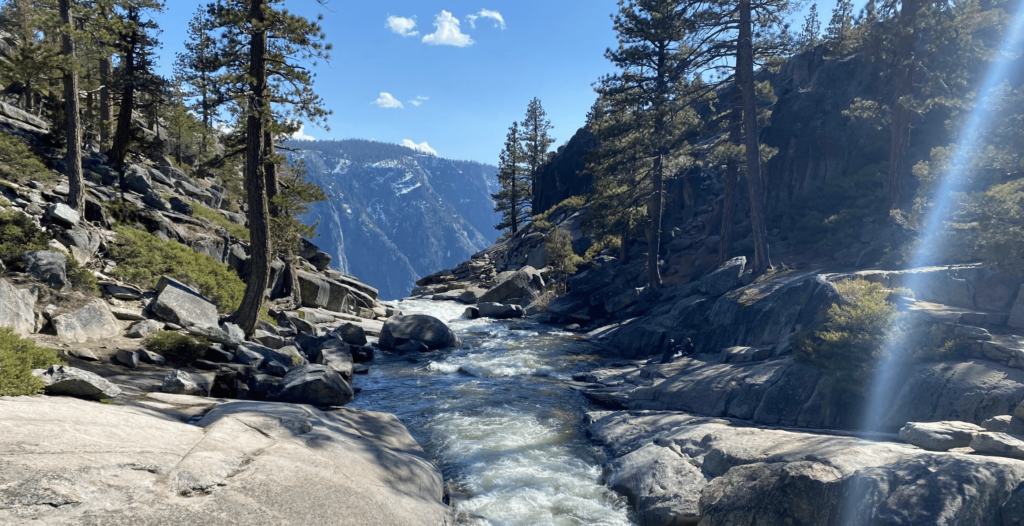 little stream running through rocks with a view of yosemite mountains in the background
